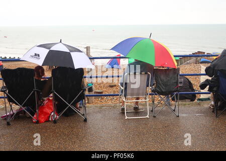 Eastbourne, Großbritannien. 18. Aug 2018. UK Wetter. Besucher in Eastbourne einen Regen tapfer Dusche während des Wartens auf das Fliegen am Tag 3 der International Air Show, Eastbourne, Großbritannien zu starten. Credit: Ed Brown/Alamy leben Nachrichten Stockfoto