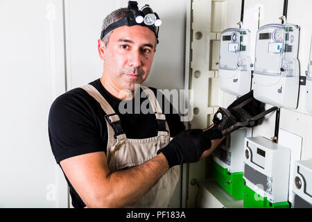 Elektriker Prüfung Sicherungskasten oder Umschalter mit Taschenlampe auf dem Kopf Nahaufnahme Stockfoto
