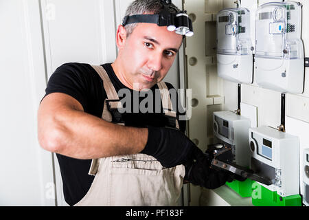 Elektriker Prüfung Sicherungskasten oder Umschalter mit Taschenlampe auf dem Kopf Nahaufnahme Stockfoto