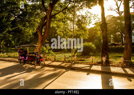 Niedrige Sonne mit einem Tuk Tuk auf einer leeren Straße in Siem Reap geparkt Stockfoto