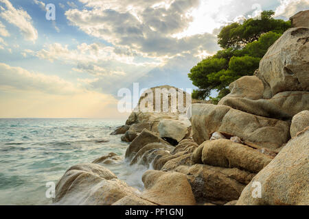 Sonnenstrahlen durch die Wolken über erstaunliche Koviou Strand und schöne rock Struktur mit einer Kiefer auf der Oberseite Stockfoto