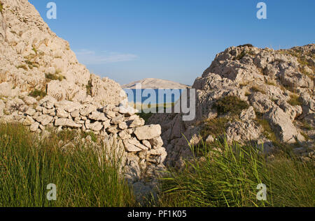 Kroatien, Europa: ein Blick von Rucica, dem Kiesstrand in einer kargen Bucht mit wenig grüne Pflanzen und Landschaft der Wüste auf der berühmten Insel Pag gelegen Stockfoto