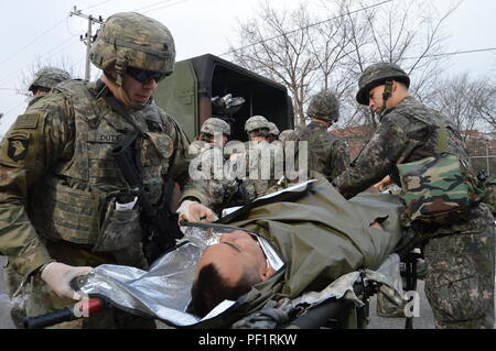 Spc. Logan Pflicht, combat Medic, Sitz und Hauptverwaltung Batterie, 6 Battalion, 52nd Air Defense Artillery Regiment, 35th ADA Brigade und einem unbekannten Flieger mit der Republik 10 Korea Air Force Fighter Wing tragen ein Soldat mit simulierten Verletzungen während ihrer kombinierten Base Defense, auf Suwon Air Base, Feb 18, 2016 statt. Die Ausbildung besteht aus einem base Angriff verursacht Masse Verluste durch eine Antenne medizinische Evakuierung gefolgt. (Foto durch KATUSA Cpl. Yo Seup Kim) Stockfoto