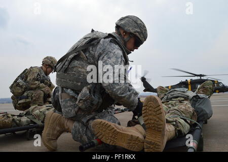 Spc. Logan Pflicht, Vordergrund, combat Medic und Kapitän Hyun Yi, Arzt Assistent, sowohl an die Zentrale und Sitz der Batterie, 6 Battalion, 52nd Air Defense Artillery Regiment zugeordnet, 35. ADA Feuerwehr bereiten Soldaten, die simulierten Verletzungen für medizinische Evakuierung auf der Erwartung Hubschrauber während ihre kombinierten Base Defense, auf Suwon Air Base, Feb 18, 2016 statt. Das Training bestand aus US-Soldaten und der Republik Korea Luftwaffe Flieger Verteidigung der Basis gegen einen Angriff durch massive Verluste. (Foto durch KATUSA Cpl. Yo Seup Kim) Stockfoto