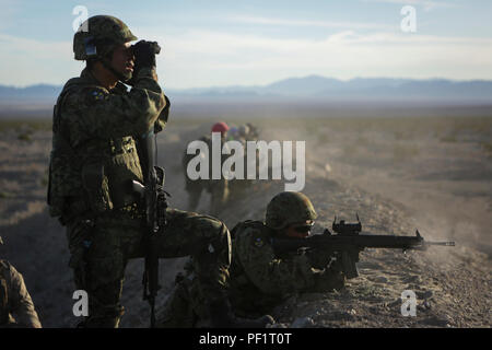 Ein rifleman zu Westliche Armee Infanterie Regiment, Japan Ground Self Defense Force zugewiesen, beobachtet die Auswirkungen, wie mehrere Service Mitglieder Feuer auf simulierte Ziele, während einer Live-fire Platoon level Angriff, während der Übung Iron Fist 2016 an Bord der Marine Corps Air Ground Combat Center Twentynine Palms, Feb 9, 2016. Iron Fist ist eine jährliche, bi-laterale Training zwischen den Japan Ground Self Defense Force und Marines warfighting Fähigkeiten in ship to shore Operationen zu stärken. Stockfoto