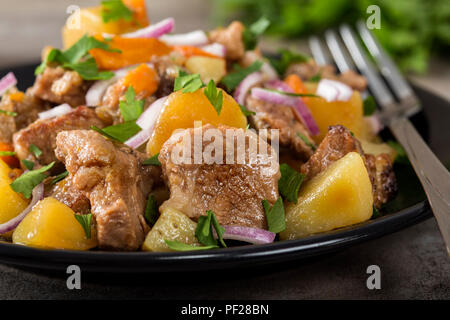 Gebackene Kartoffeln, Schweinefleisch und Karotten auf Platte mit Kräuter Stockfoto