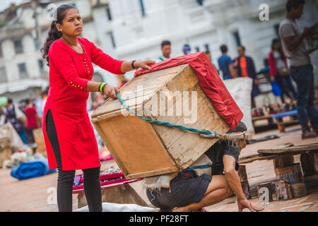 Kathmandu, Nepal - Apr 11,2018: Am frühen Morgen, Nepalesische Porter, die sehr schwere Last von Souvenir Ausrüstungen auf Ihre an basantapur ausgeht, Kathmandu. Die Stockfoto