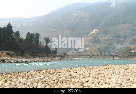 Rocky Riverside und die Brücke über den Fluss Puna Tsang Chu in Khuruthang, kleine Stadt in der Nähe von Punakha, Bhutan Stockfoto