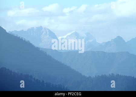 Morgen Berglandschaft mit Schicht Berggipfel mit Nadel-und Laubwäldern bedeckt. Blick vom Dochula Pass auf dem Weg von Thimphu Stockfoto