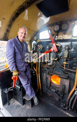 Der Fahrer eines Dampfzug auf der Fußplatte vor der Abreise von Minehead Station auf der West Somerset Railway, England, Großbritannien Stockfoto