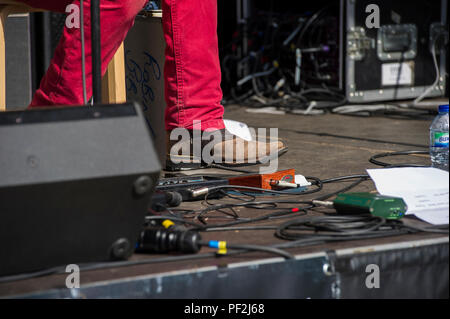 Ein blues Fuß in Cowboystiefeln Taps aus dem Rhythmus auf eine verstärkte Stomp Box an einem Open Air Festival an einem heißen Tag in London. Stockfoto