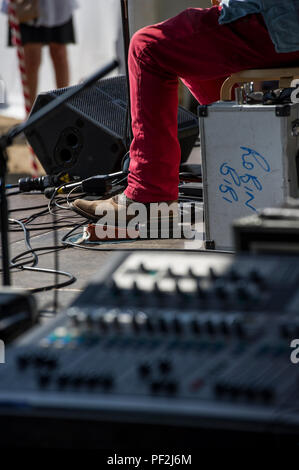 Ein blues Fuß in Cowboystiefeln Taps aus dem Rhythmus auf eine verstärkte Stomp Box an einem Open Air Festival an einem heißen Tag in London. Stockfoto