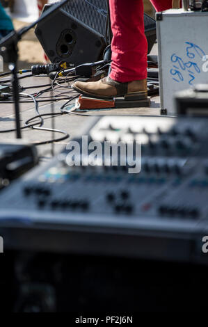 Ein blues Fuß in Cowboystiefeln Taps aus dem Rhythmus auf eine verstärkte Stomp Box an einem Open Air Festival an einem heißen Tag in London. Stockfoto