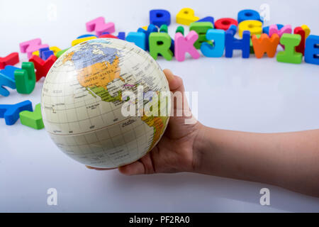 Kleines Modell gobe in Hand mit bunten Buchstaben hinter Stockfoto