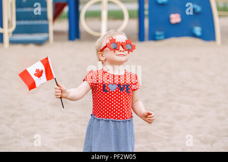 Portrait von adorable kleine süße blonde kaukasische Baby Kleinkind Mädchen, dass kanadische Flagge. Weibliches Kind tragen lustig Ahornblätter Sonnenbrille celebrat Stockfoto