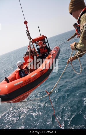 Armee Mariners mit der 1099Th Transport Loslösung der SP4 James A. Loux, Logistik Unterstützung Fahrzeug-6, ziehen in ihrer Rettung Boot nach einer Mann-über-Bord-Notruf Bohrers, während im Persischen Golf, Feb 29, 2016. Eine lebensgroße Attrappe wird anstelle einer realen Person aus Sicherheitsgründen verwendet. Stockfoto