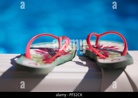 Flip Flops am Rand des Swimming pool Stockfoto