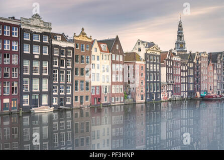 Die Häuser an der historischen Damrak Canal, in Amsterdam, in den Gewässern der Kanal bei Dämmerung wider. Stockfoto