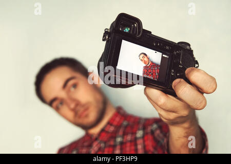 Self Portrait von fröhlichen, bärtigen Blogger in Shirt shooting selfie, Video für seinen Blog auf gelben Hintergrund. hübscher junger Mann unter pictu Stockfoto