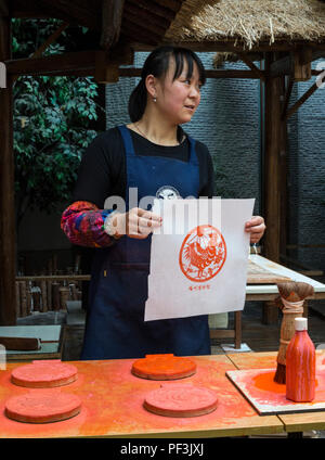 Yangzhou, Jiangsu, China. China Block Printing Museum. Artist Holding Drucken aus Holz geschnitzte blockieren. Stockfoto