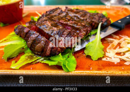 Traditionelle italienische Tagliata Steak mit Parmesankäse und Salat als Close-up auf einer Platte Stockfoto