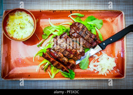 Traditionelle italienische Tagliata Steak mit Parmesankäse und Salat als Close-up auf einer Platte Stockfoto