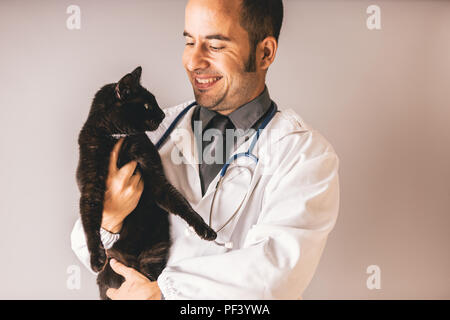 Eine Tierärztin mit einem Stethoskop um den Hals hält eine schwarze Katze und Lächeln Stockfoto