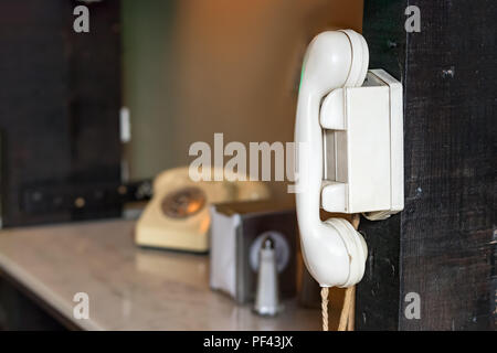 Ein Jahrgang an der Wand montierte Gegensprechanlage mit weißem Kunststoff mit einem Vintage Telefon als unscharfer Hintergrund gemacht. Stockfoto