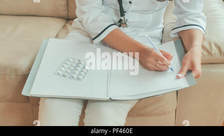 Eine junge Frau Doktor schreibt verschreibungspflichtige Medikamente und Behandlung beraten. Stockfoto