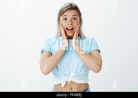 Portrait von schockiert attraktive Frau zittern Von der Überraschung und positive Aufregung, halten sich an den Händen in der Nähe von Mund und breit grinsend mit geöffnetem Mund, sehen fantastisch und unglaublich Stockfoto