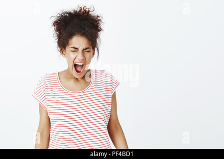 Mädchen können nicht Druck mehr. Portrait von Angry unglücklich dunkelhäutige Frau in gestreiften T-Shirt, schliessen die Augen und schrie vor Wut und verzweifelt fühlen, Probleme und wollen gehört werden Stockfoto