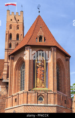 Ein Fragment der Südseite der mittelalterlichen, erbaut aus rotem Backstein, Schloss des Deutschen Ordens in Marienburg, Danzig Pommern in Polen. Historische Statue von Maria, Stockfoto