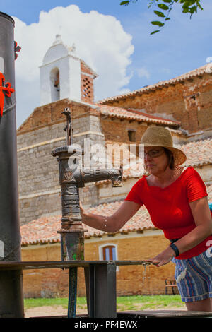 Frau, die den Wasserbrunnen der Emita de la Virgin del rio benutzt, während sie auf der spanischen Pilgerroute den Jakobsweg entlang geht Stockfoto