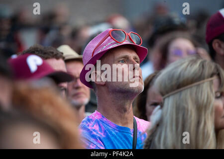 Glanusk Park, Brecon, Wales, 18. August 2018. Tag 2 des Green man Musikfestivals in den Brecon Beacons Mountains in Wales. Ein Mann mit einem rosafarbenen Strohhut und herzförmigen Farben. Allgemeine Aufnahmen der Menge und des Ortes während des Festivals – der ummauerte Gartenbühnenbereich. Quelle: Rob Watkins/Alamy Live News. Stockfoto