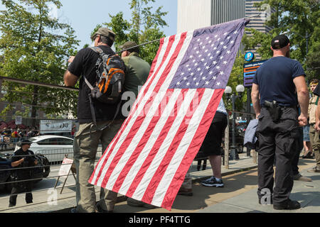 Seattle, WA, USA. 18 August, 2018. Pro Waffe Verfechter der amerikanischen Flagge beobachten counterprotesters auf der anderen Straßenseite auf der 4th Avenue vor dem Rathaus. Credit: Maria S./Alamy Leben Nachrichten. Stockfoto
