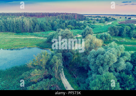 Schönen Abend Landschaft. Blick von oben auf die Landschaft. See auf einer Wiese, Wald und Land straße Stockfoto