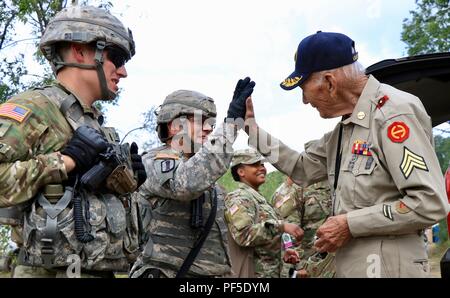 CAMP ÄSCHE, Mich - Weltkriegveteran, Claude Cawood, gibt Jeffery Lemire, erster Sergeant, Batterie A, 1st Bataillon, 103 Field Artillery Regiment, Rhode-Island Army National Guard eine hohe - fünf nach dem Feuern der M777 Haubitze, Aug 9, 2018 in Camp Äsche, mich Cawood, einem ehemaligen Section Chief auf der M105 Haubitze, der drei Jahre auf den Philippinen gedient hatte Gelegenheit, Soldaten zur Unterstützung der Northern Strike übung zu besuchen. (U.S. Army National Guard Foto von 1 Sgt. Sara Robinson) Stockfoto