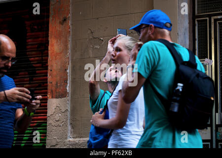 Ein Mann nimmt ein Foto auf seinem Smartphone während touristische Push an ihm vorbei, Gracia, Barcelona. Stockfoto