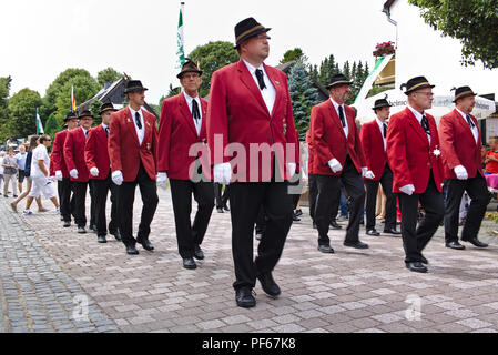 Usseln, Deutschland - Juli 29th, 2018 - Rifle Club Mitglieder in ihrer traditionellen roten Uniformen an der Sportschützen ist fair paradieren Stockfoto