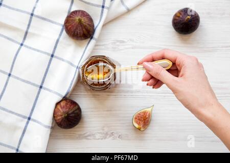 Eine weibliche Hand hält einen Löffel mit feigenmarmelade, Ansicht von oben. Von oben und Overhead. Stockfoto