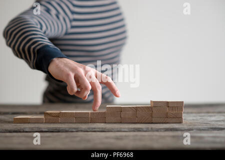 Die Anzahl der Blöcke, die auf eine Tabelle der allmählich zunehmenden Höhe mit den Fingern einer Hand heraus Rückverfolgung der Aufstieg. Metapher für Business entlang t Stockfoto