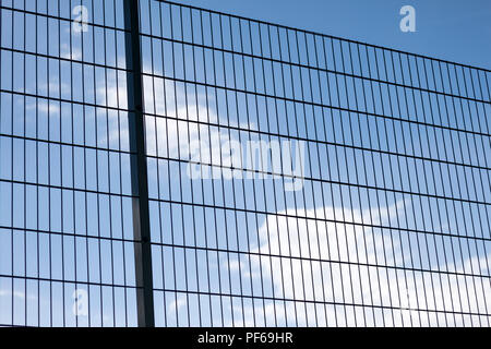 In der Nähe von hoch abstrakten geometrischen schützende Dark Metal Zaun von Fußball- oder Fußballplatz Spielplatz am klaren, blauen Himmel mit weißen Wolken ba Stockfoto