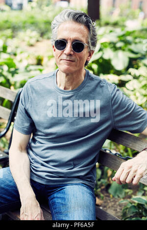 Grauhaariger Mann sitzt auf einer Parkbank Stockfoto