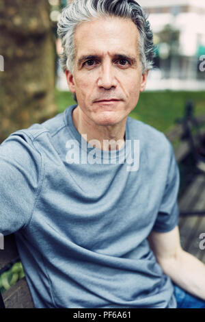 Grauhaariger Mann sitzt auf einer Parkbank Stockfoto