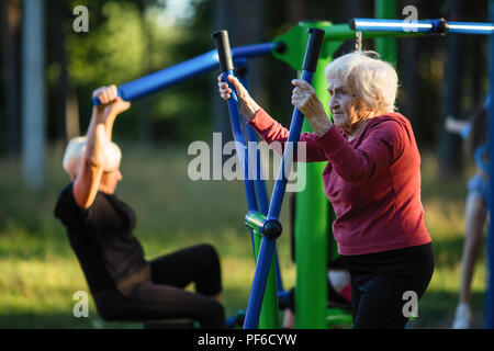 Ältere Frau ist Übungen auf dem Spielplatz im Park. Stockfoto