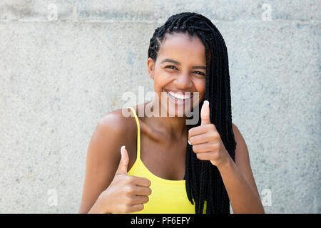 Glücklich lachend afrikanische amerikanische Frau mit Dreadlocks, Daumen im Freien im Sommer Stockfoto