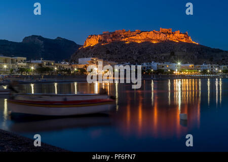 Blaue Stunde bei Haraki (MOI) mit Blick auf den Hafen und die Burg in der Ferne die Insel Rhodos, Griechenland Stockfoto