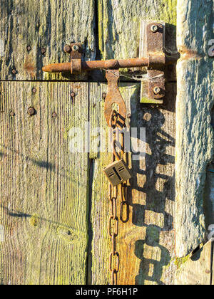 Altes Schloss und Kette auf verwitterte Scheunentor - Frankreich. Stockfoto