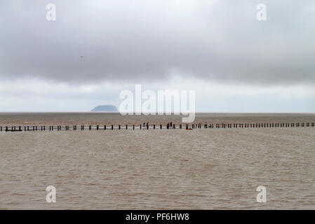 Wandern am Wasser bei Weston Super Mare, Somerset, England, UK. Urlauber Spaziergang entlang dem Meer pool Wand vor der Kulisse des Bristol Channel. Stockfoto