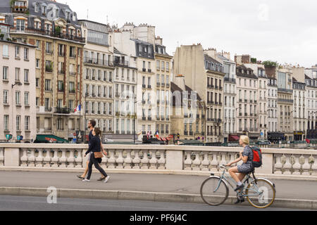 Paris Stadtbild - Frau Radfahren über die Saint Michel Brücke, Gebäude am Quai des Grands Augustins sind im Hintergrund. Paris, Frankreich, Europa. Stockfoto